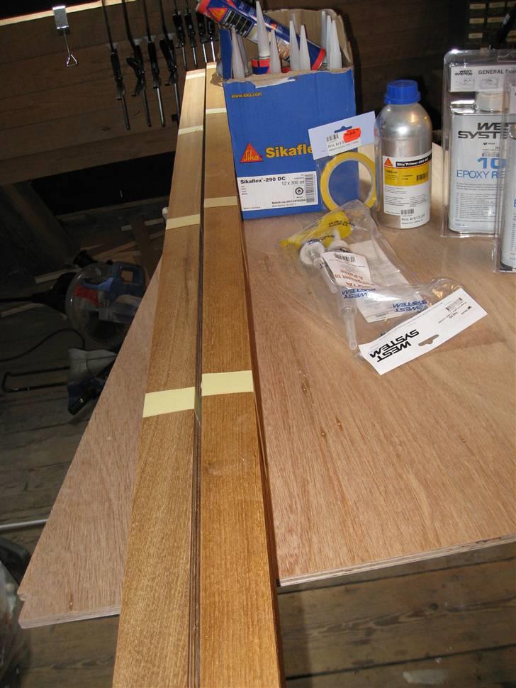 Hjemmelavet teakdørk - Materialer:
Østen xfiner 12mm
Teakbordplade strimlet op. 6mm tykkelse, 45mm brede.
West System Epoxy 2 komponent. (til at lime listerne fast)
Sika nåddetape.
Sika Primer 290 DC, Sika Flex 290 DC
 billede 1