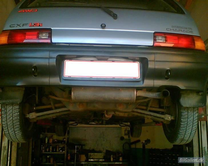 Daihatsu Charade Udstyr og Varianter - Her ses så en model variant CFX 4WD
Betegnelsen CFX står for:
C = Det står for at det er den 5 dørs model.
X = ekstra udstyr i form af flere forskællige ting bla. dørlommer.
F = 4WD det står for at bilen er udstyret med Full Time 4WD, altså permanent firehjuls træk.

Der er nogle få ændringer på en 4WD model og model betegnelsen er også G112 og ikke G100 eller G102, men faktisk kan den fåes i både G100 og G102 varianten, min egen som der er billed af her er en G112 bygget over G100 karossen. med de kortere kofangere og ude refleks stykker på for kofangeren. samt spænde seler på bagsædet.

Af ændringer på en G112 kan nævnes følgende:

Bagpotten/udstødnings potten ligger på tværs fordi bagtøjet til 4WDet og træk axlerne gør at der ikke er plads til at have den på langs af bilen hen under bagbroen.
Af ovennævnte grunde er tanken også mindre og anderledes udformet og indeholder 32 Liter i forhold til en G100 og G102 som kan rumme 37 Liter.
Derfor er tankmåleren i instrument panelet også af en anden type med påskriften 4WD på bagsiden hvis man altså har instrumentet ude.
Tank måleren viser også konstant tank indholdet frem for G100 og G102 som kun viser det når bilen slåes over på tænding.

Grundet den tungere bagende og her monteret 200mm tromle bremser i stedet for de org. 180mm.
bremse cylinderne til dem er også specielle af den grund.
De foreste er standart faste skiver.
samtidig for at kapere den ekstra vægt på 105 Kg en 4WD model vejer er den udstyret med kraftigere støddæmpere og fjedre på bagaxlen, da vægten hoved saglig er forøget her pga. bagtøj træk axler og ekstra ophæng osv.

G100 og G112 modellen har også 2 træk kroge der stikker ud gennem kofangeren hvor G102 kun har den i venstre side. billede 5