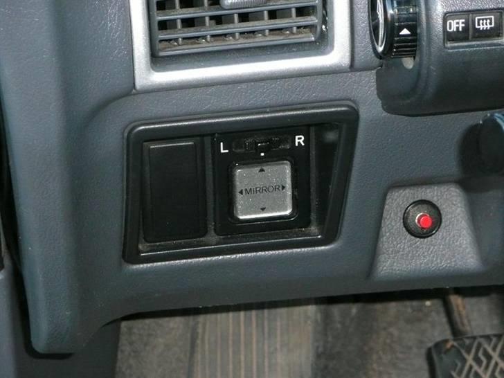 Daihatsu Charade Udstyr og Varianter - Bilen her er udstyret med Elspejle i begge sider og det er en stor hjælp da en Charade normalt er født med manuelle spejle som kun kan indstilles ude fra og ikke fra kabinen med en pind som det er tilfældet på mange andre biler med manuelle spejle.

Rammen ved siden af elspejle justeringen er til forskælligt udstyr så som lygtehøjde justering til forlygterne, andre ting så som tågelygter fortil eller lygte vaskere kunne også være formålet.
Jeg ved at lygtevaskere var ekstraudstyr som kunne fået i Sverige, Norge og Finland, men ikke i DK.
Og jeg har så vidt aldrig set en Charade med tågeforlygter org.
Så jeg tror den har været til lygtevasker systemet.

De sølvmetallic farved luftindsugnings rammer er dog custom lavet og ikke noget en Charade kunne fåes med, men det pynter gevaldigt i den så grå og kedelige kabine. billede 8