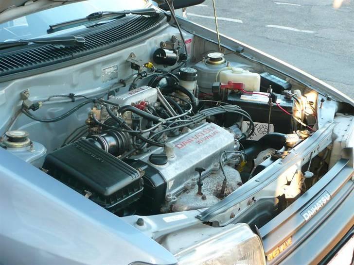 Daihatsu Charade Udstyr og Varianter - Her er motorrummet på min G112
Den har gået under 100.000 Km og så skal et motorrum ikke se meget snavset ud eller olieret før det kan afslørre at Km ikke paser med virkeligheden, men det er der ingen tvivl om her også hvad rust angår, så er manifolds varmeskjoldet stadig utrolig rustfrit hvad det ellers ikke plejer at være på mange charader og nogle mangler det helt.

Det skal siges der ikke er fortaget motorvask på denne bil de sidste 3 år, før det ved jeg ikke da den er født i Sweitz men sådan som gulli og plastik samt metal næsten fremstår som nyt så kan bilen ikke være kørt i sne og slud og det er jo en god ting :o)
Her ses i øvrigt at G100 modellen som min G112 er bygget over har den røde skrift på topdækslet og indsugnings agragatet. samt i fronten. billede 13