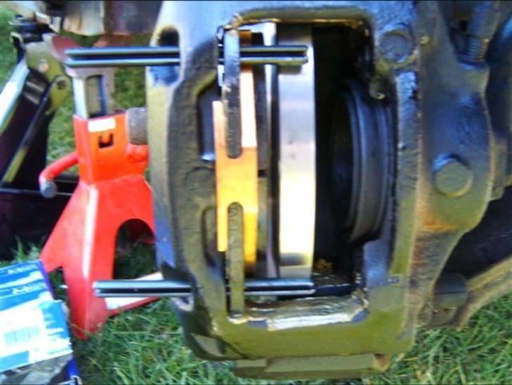 Skift af bremseklodser og skiver - En klods sættes ind og den øverste split sættes halvvejs ind, den nederste split sættes lige ind i klodsen så fjederen kan komme på, fjederen trykkes ind så splitten kan gå forbi. billede 14