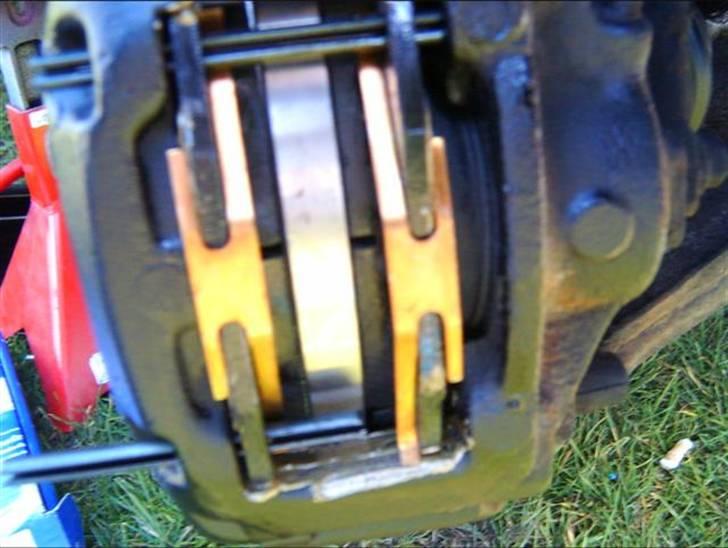 Skift af bremseklodser og skiver - Den anden klods sættes i, og den øverste split bankes på plads. Fjederen sættes på, og trykkes ind så splitten kan gå forbi. Så bankes den nederste split på plads. billede 15