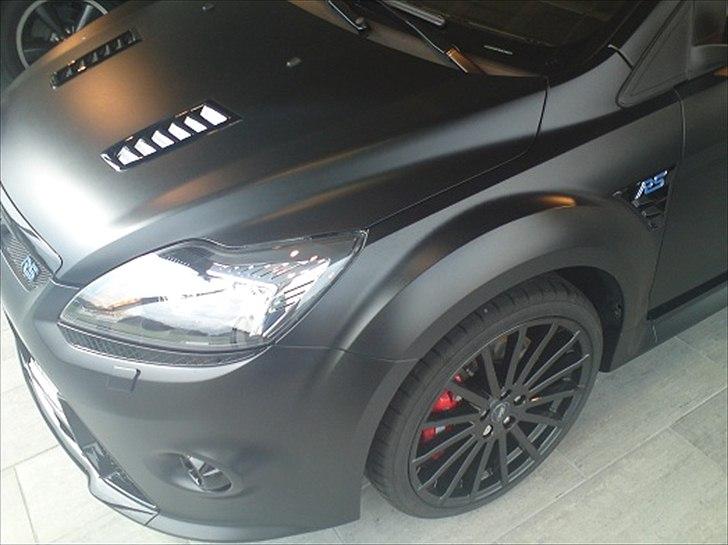 Focus RS 500 hos Brdr. Hosbond i Aalborg - Syntes selv det en lidt fed vinkel skrå forfra :)...

"Alle Focus RS500 bliver malet i standard Panther Black metallic inden de bliver transporteret til virksomheden 3M ved Frankfurt. Her bliver der påført en speciel folie for at give den matsorte effekt. Folien er ekstremt holdbar og designet til at modstå stenslag og småridser. Ved skader rykker en specialist fra 3M ud til ethvert autoriseret Ford-værksted i Europa, der udfører lakreparationer på bilen." billede 2