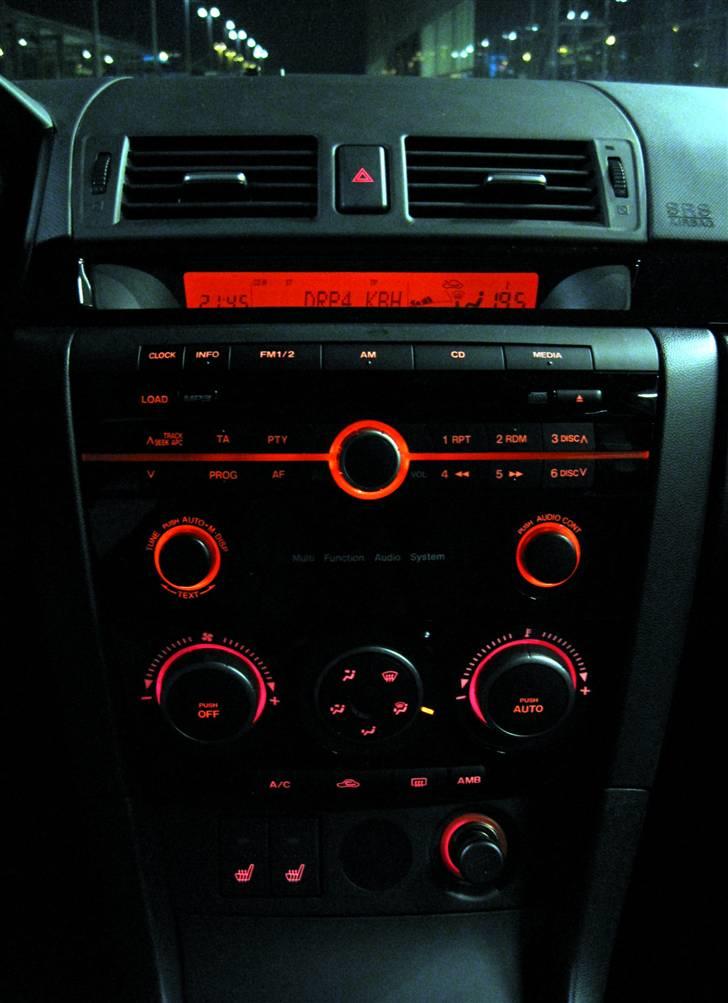 Mazda 3 DE Inclusive (Solgt) - Natbelysning af midterkonsol - bemærk infopanel som giver alt fra radio, klima til hvor langt til næste tankning billede 8