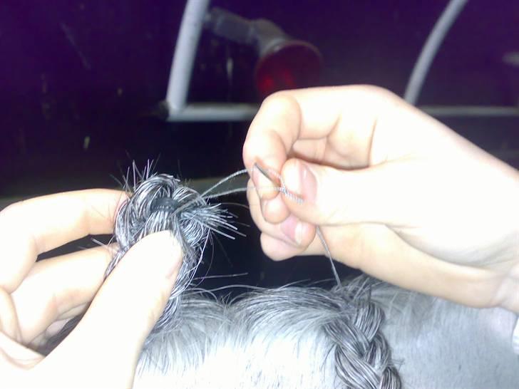 Flette-guide til rosenknopper - Klip en tråd på ca 80 cm. Stik den igennem nålen og læg den dobbelt. Bind en knude på enden.

Bøj elastikenden ind bag fletningen og stik nålen igennem. Stik nålen igennem enden på tråden, inden du trækker tråden helt ud. billede 16