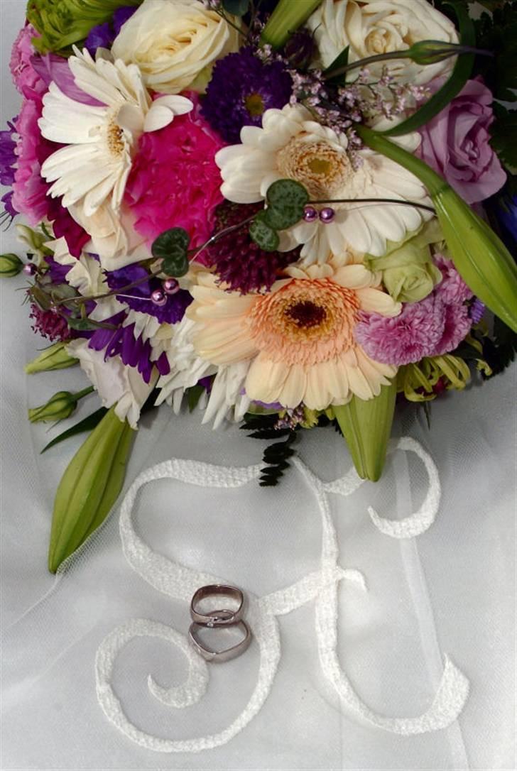 Bryllupsbilleder - Buketten er bundet af blomster medbragt af gæsterne. Vores blomsterhandler stod ved kirken og bandt den ligen inden jeg ankom. 
Ringene er lidt firkantede, og har begge et halvt hjerte i mønstret, og i min er der en diamant.
Monogrammet har jeg selv designet og det er broderet på sløret. billede 3