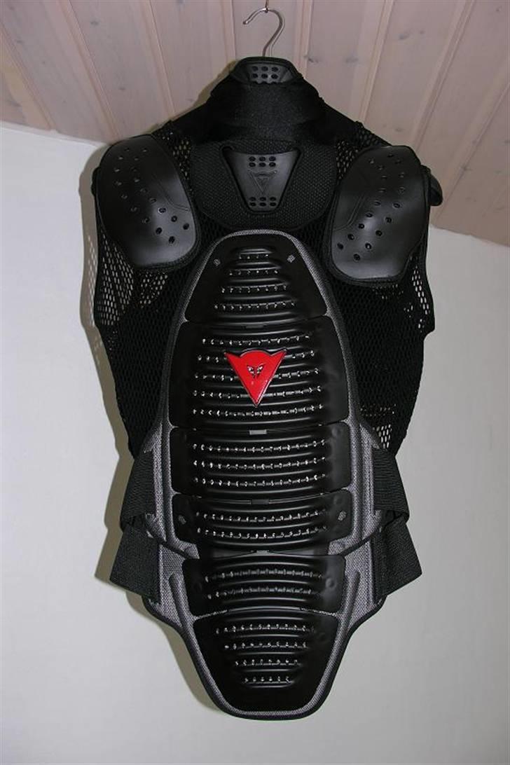 Dainese Gilet Wave 2 Neck - Det helt specielle ved denne udgave er selvfølgelig nakkebeskytteren (deraf navnet "Wave 2 Neck"), det var en af de detaljer, jeg syntes var en rigtig god ekstra beskyttelse.

DESVÆRRE duer den nakkebeskytter absolut ikke til mig og min nakke/kørestilling. Vesten sidder perfekt indtil jeg får resten af udstyret på, med jakken udover er den næsten lige så fleksibel som før, men når hjelmen kommer på (Shoei - Raid II) går det helt galt.
Det betyder at nakkebeskytteren borer sig op under hjelmen og ind i det "hul" der er i baghovedet, så når jeg kommer på cyklen (GSX 600 F) generer det helt vildt, specielt når jeg drejer hovedet, og mindsker derved mine orienteringsmuligheder. billede 3