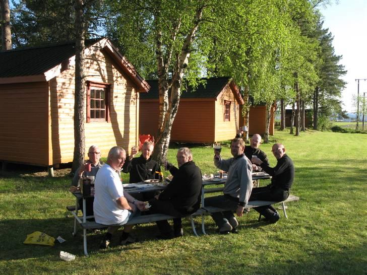 Norge Klanen indtager Polarcirklen - Hytterne i Nomsos var pragtfulde. Køkkenet havde vi for os selv. Bordene blev slæbt ud i solen. Maden blev tilberedt dels i køkkenet, dels over gril. Vi fejrede Bedstefar var blevet Bedstefar igen. Skål og tillykke med den lille nye verdensborger. billede 28