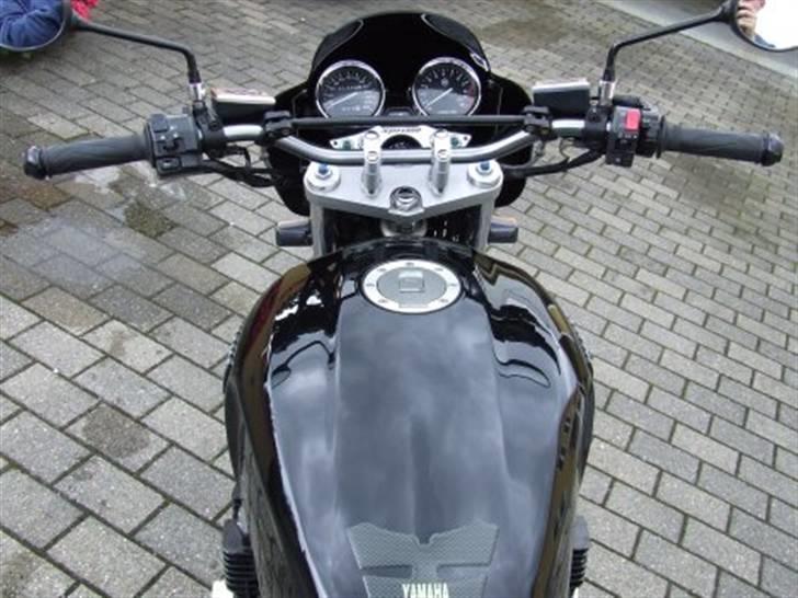 Yamaha XJR 1300 (solgt) - Det brede styr giver god kontrol over cyklen, og sammen med et sæt raisers en fin kørestilling. Desuden er forgaflen sænket 10 mm. gennem broen, hvilket har gjort den mærkbart mere styrevillig (og sjov!) Derudover er der monteret en Givi-lygtekåbe. billede 6