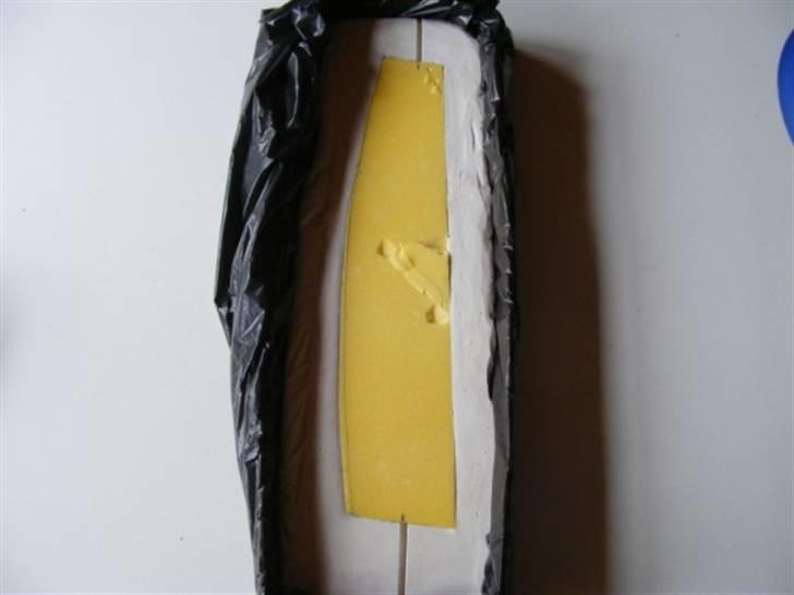 Forlængelse af køl på Sea Queen - Rør gipsen sammen ud fra anvisningen på pakken. Ud fra anvisningen fremgår det at man kan arbejde med gipsen op til 15 min. Hæld massen ned i formen, vip formen lidt op og ned for at få så mange luft bobler ud i ca 10. min. Smør Depronskabelonen godt med farveløs skosværte, husk kanterne.
Mas skabelonen ned i massen, og lad den sidde en times tid.
Fjern Depron skabelonen ved at stikke en lille skrue trække side værs ned i Depronen, pas på den at den ikke går igennem skabelonen. Lirk skabelonen ud. billede 11