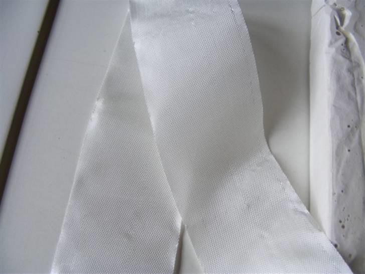 Forlængelse af køl på Sea Queen - Kan ikke lige huske hvilken type glasfiber måtte jeg brugte - tror det var 150g. Prøvede først med noget kraftigere, med der kom for meget luft i, og gav gevaldige huller under slibningen. 
Her kan man se strukturen og få en fornemmelse af hvad type jeg brugte.
Klippe 10 stykker ud efter Depron skabelonen.
Starte med at hælde lidt færdig rørt polyester ned i formen - lagde derefter 5 stykker glasfiber, derefter gevind stangen - vær opmærksom på mærkerne som tidligere beskrevet, derefter mere polyester så gevindstangen næsten var dækket. Glattede det lidt ud med en pensel for at få fjernet så meget luft som muligt. Lagde de resterende 5 stykker glasfiber oven på, og igen glattede det ud for at fjerne luft. Hældte til sidst det resterende polyester oven på så det lige løb ud over kanten.
Dette væv er købt hos ICCOM for ca. 150,-kr pr m2, mere end rigeligt til en 3 til 4 forsøg. billede 15