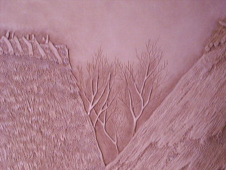 Min anden hobby 3, Læder Billeder - Her imellem hustagene, kan man se træerne.
Stammerne og de tykke grene er punslet så de er fremhævet, imens de tynde grene bare er skåret ned i læderet.
Tagbelægningen har jeg først formet lagende af strå, så rillet taget/stråene op, og så hakke det over med en pikket punsel så det ser gammelt og lidt trøsket ud.
 billede 44