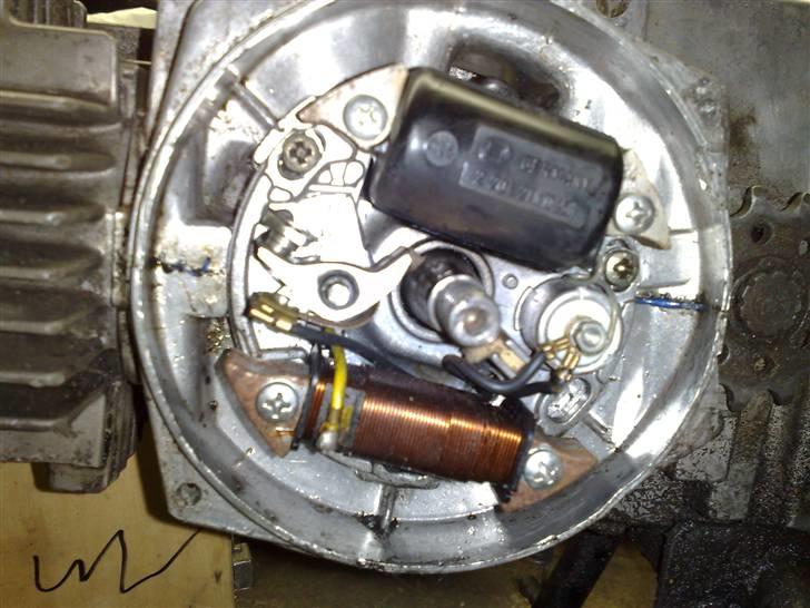 Justering af tænding på en puch maxi - 1 lysspole for neden
tændspole for oven
kontensatore højer
platiner til venstre også kaldt kontakter
det som det hele sider på heder en ankerplade husk bagside skal være pinlig rent ikke noget med olie eller maling,den sider fast med 3 skruger som man kan løsne og fin justere tending med for eller eftertending,det kommer sener billede 1