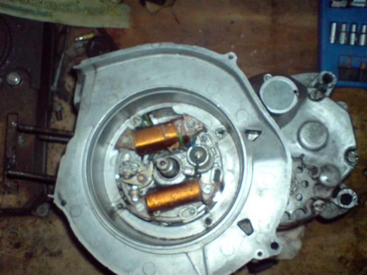 Renovering af puch motor. - 2 gear automatic handikap. - Tændingen, ikke noget at komme efter her. Fødespole (denne model er med udenbors tændspole), lysspoler, kondensator, og platiner. Alt sammen i fin stand. Et hurtigt snor på svinghjulet inden det blev afmonteret udløste osse en sund gnist, så det fejler sq nok ikke noget. :)

Blæserskjoldet fjernes som det første, det sidder med sølle 4 skruer, så det er hurtigt klaret. Selve ankerpladen sidder med 3 skruer, så det er sq nok heller ikke det der skal holde mig vågen om natten. :) billede 12