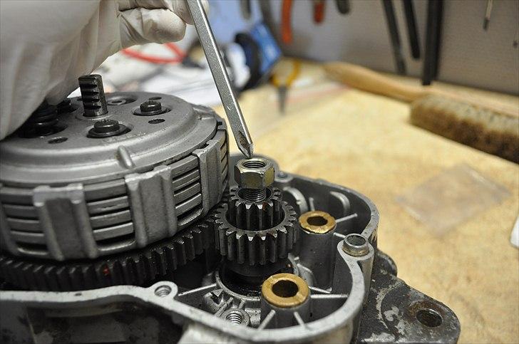 6 trins gearkasse [Derbi Senda] - Sæt den i gear og løsn den udpegede møtrik. Billede 1-4 kan være meget nemmere, hvil blokken stadig sidder på knallerten, da man skal holde igen på den aksel hvor fortandhjulet sidder når denne møtrik løsnes.  billede 4