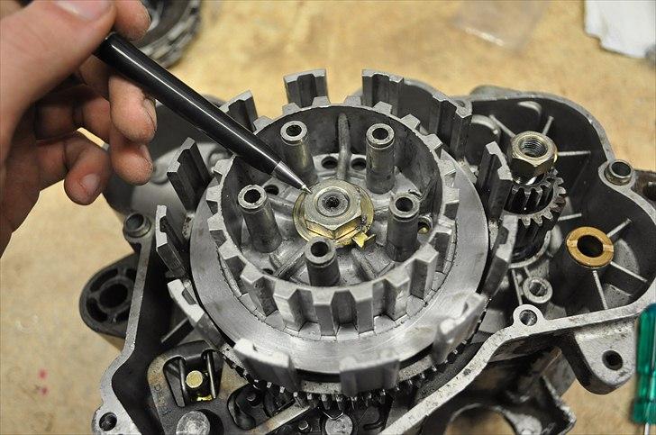 6 trins gearkasse [Derbi Senda] - Løsen den udpegede møtrik. Endnu en møtrik der er nemmest at løsne hvis blokken sidder på knallerten. Luftnøgle kan anbefales hvis ikke motoren sidder på knallerten. billede 12