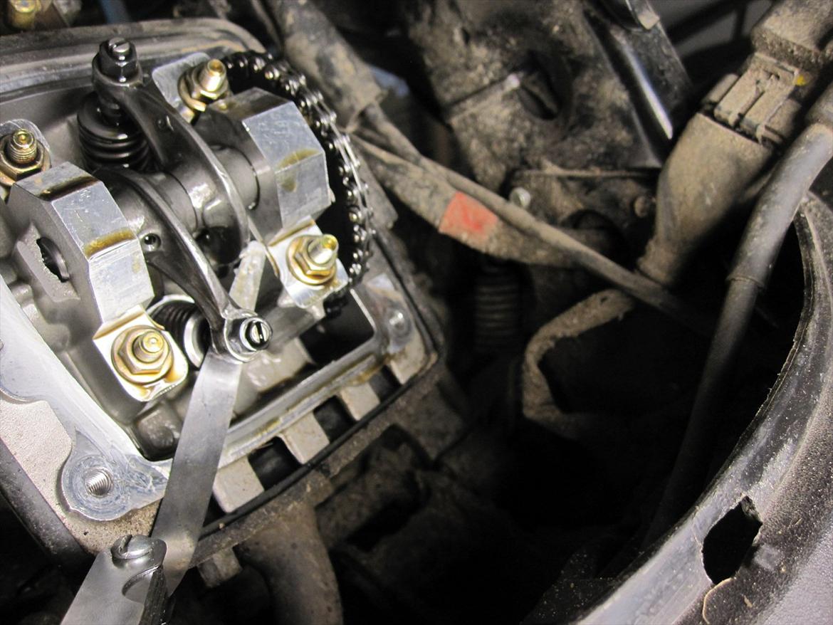 Guide: Indstilling af ventiler på Zip 4-takt - Drej nu motoren rundt, så du er sikker på et vippearmene er væk på knasten og kun køre der hvor der IKKE går opad.
Nu kan du stille dine ventiler, ved at tage søgebladet ind under vippearmen. For at justere ventileren skruer man på skruen frem eller tilbage. 
Man skal kunne mærke noget modstand i søgebladet, men den skal ikke gå alt for stramt..
Indsugning og udstødning skal have 0,10mm.

Når du har gjort dette spænder du det sammen igen, sørger for at motoren kan køre rundt og så samler du toppen igen. billede 7