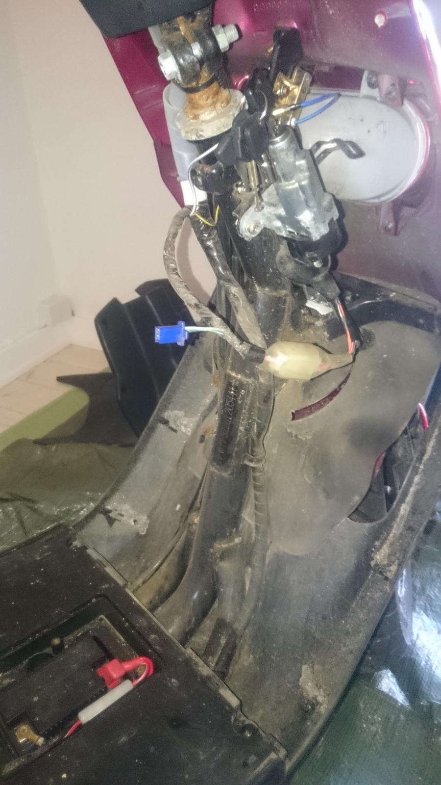 Varme i håndtag - montering - Skjoldet ved tændingen er fjernet samt gummi måtten og låget til batteriet. billede 1