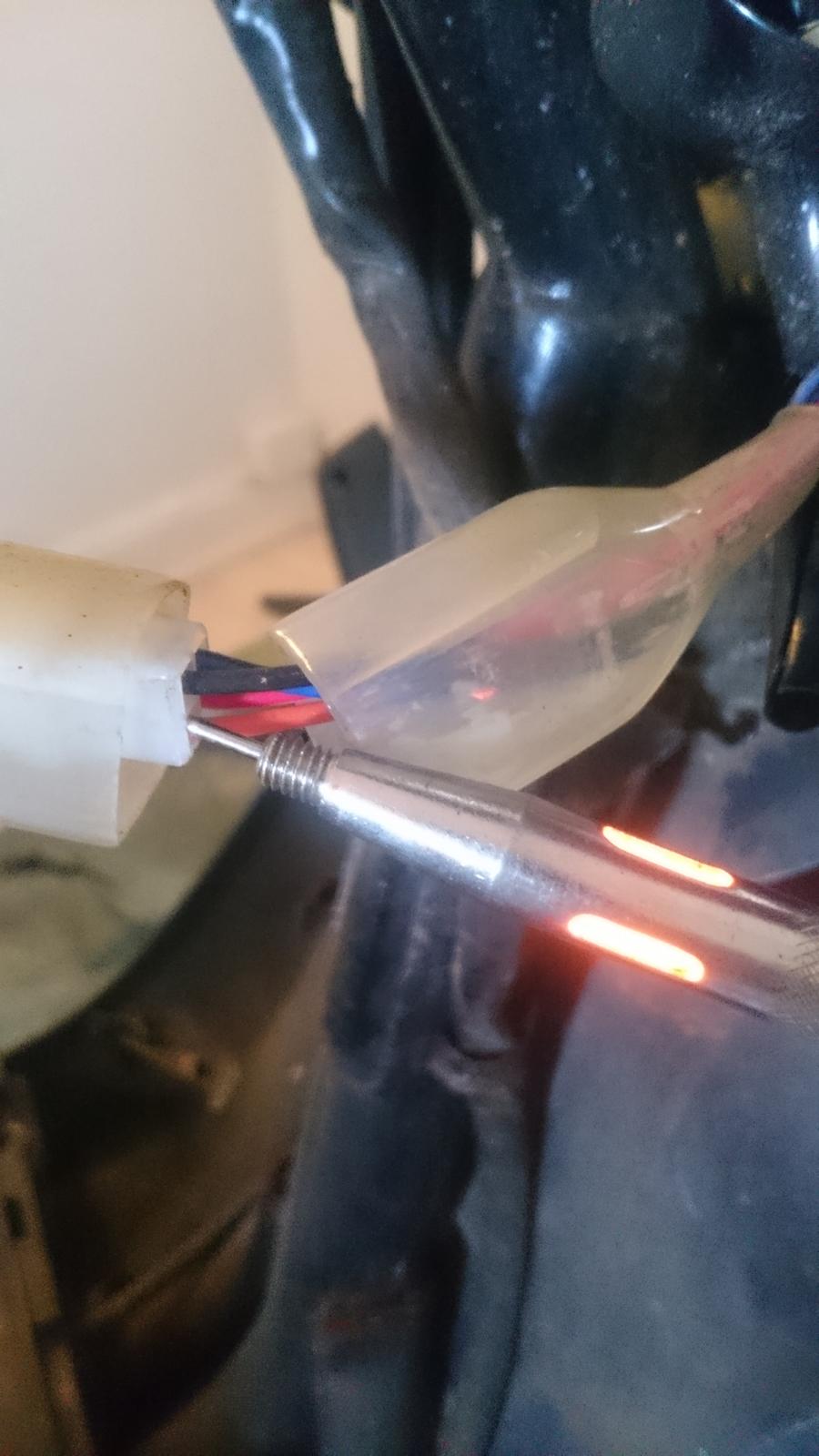 Varme i håndtag - montering - Jeg vælger at montere Plus ledningen ( Den Røde ) på tændings plusen, så hvis man skulle glemme at slukke for varmen så kan den ikke aflade batteriet, da det så kun virker når der er tænding på. For at finde tændings plusen, bruger jeg en prøvelampe som lyser hvis der er gennemgang. slår jeg tændingen fra, slukker de, så jeg ved at jeg har fat i den rigtige. ( den Orange )  billede 2