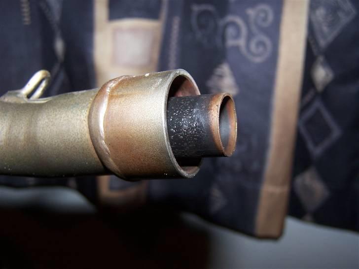 Hvordan man fjerner begrænsning i udstødning - Her er der et billede fra siden af hvor man bedre kan se den stikker ud. :)
Det stykke der stikker længere ud, det sætter du fast i en skruetvinge. Maser begrænsningen helt flad simpelthen.
Herefter drejer du til den går fri. Så simpelt er det faktisk. :)
Man ødelægger ikke udstødningen eller noget som helst, da begrænsningen ikke sidder særlig godt fast. Den er kun svejset til udstødningen med sølle 2 klatter. billede 2